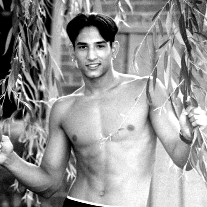 Guy as a young man, shirtless, standing among willow branches. Black and white.